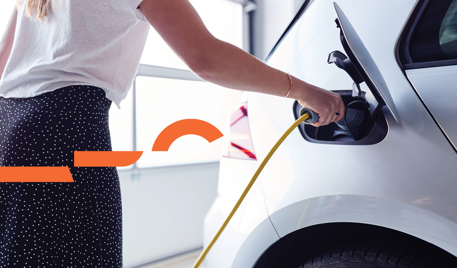 Woman plugging charger into electric vehicle