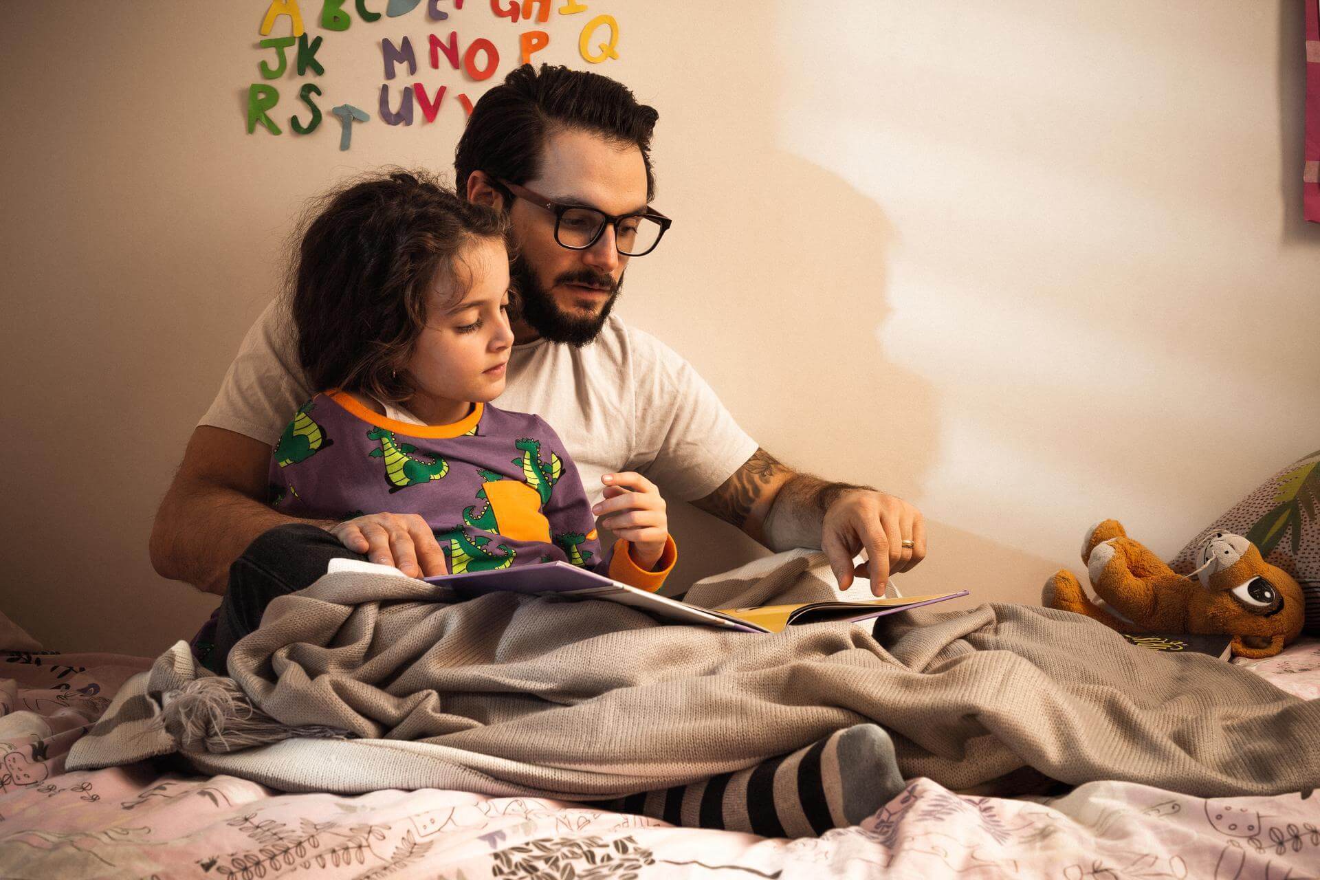 Father and child reading a book in cosy bedroom 1