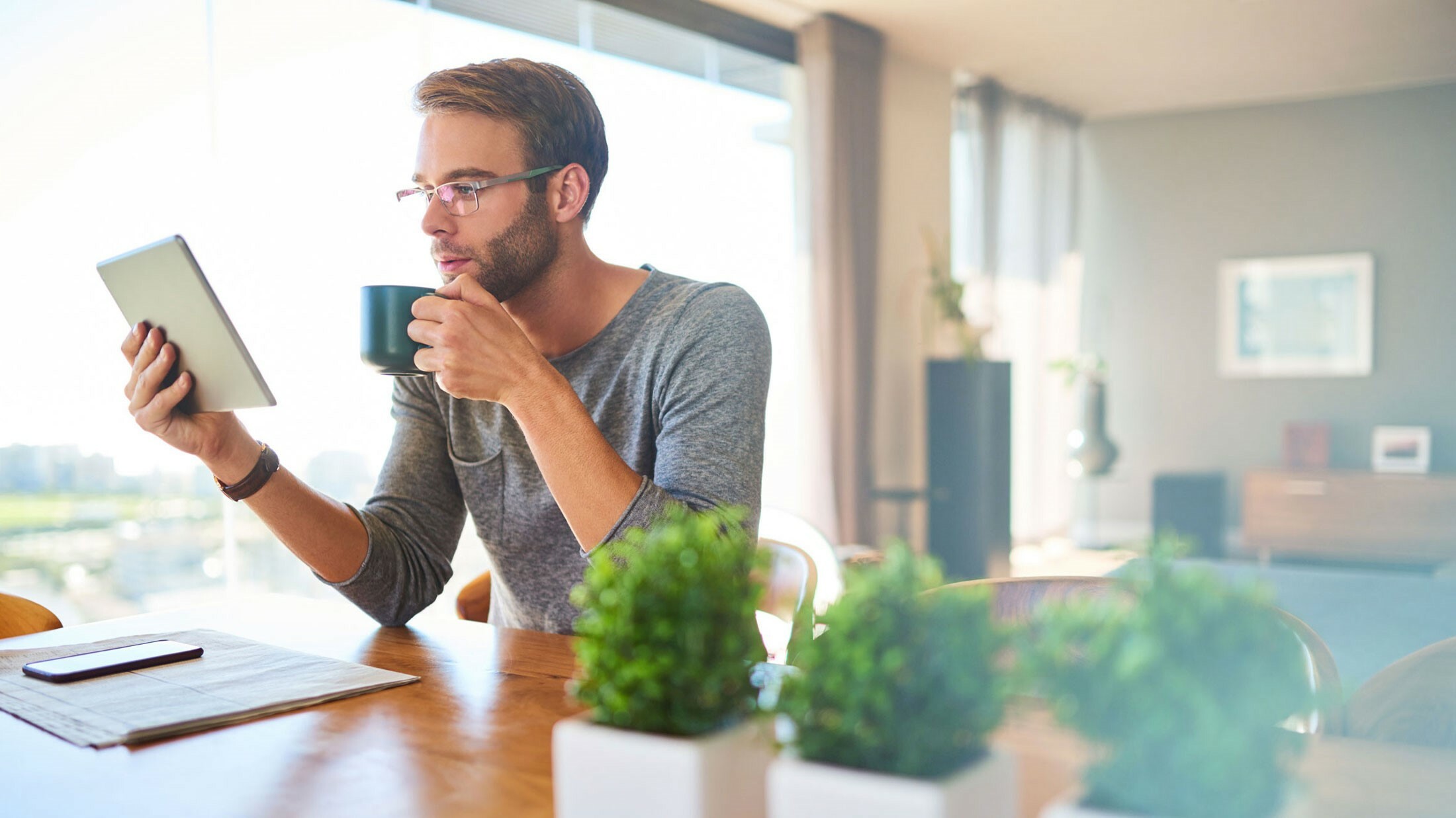 Man drinking coffee looking at iPad