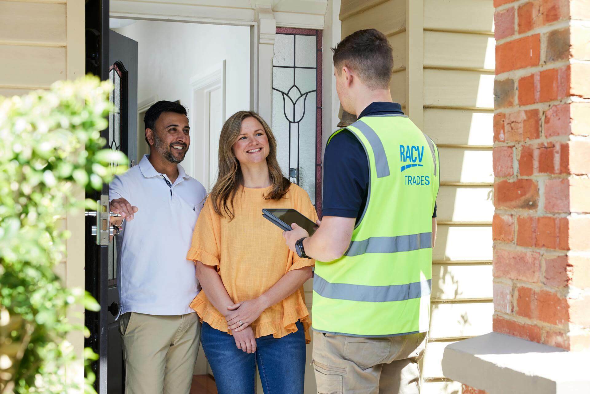 RACV tradesperson holding i Pad at front door with customers