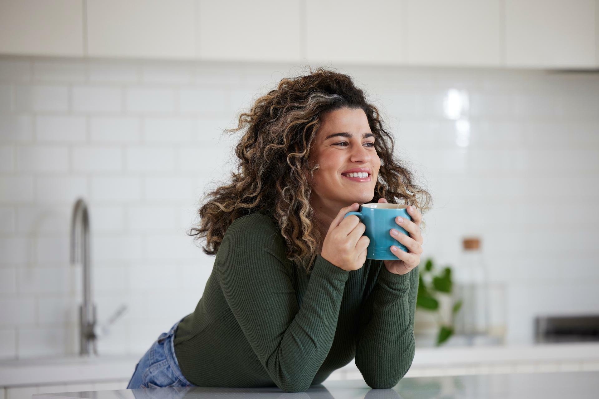 Woman holding her mug of coffee in the kitchen